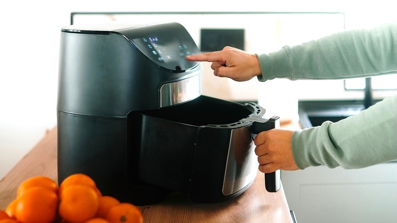 Hands preparing air fryer for use