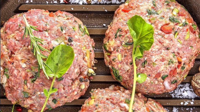 Raw burger patties with added vegetables and herbs mixed in