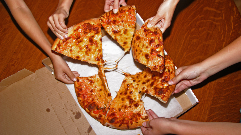 people grabbing slices of pizza