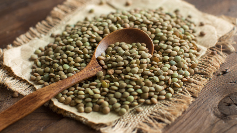 Cloth and wooden spoon covered in dry green lentils