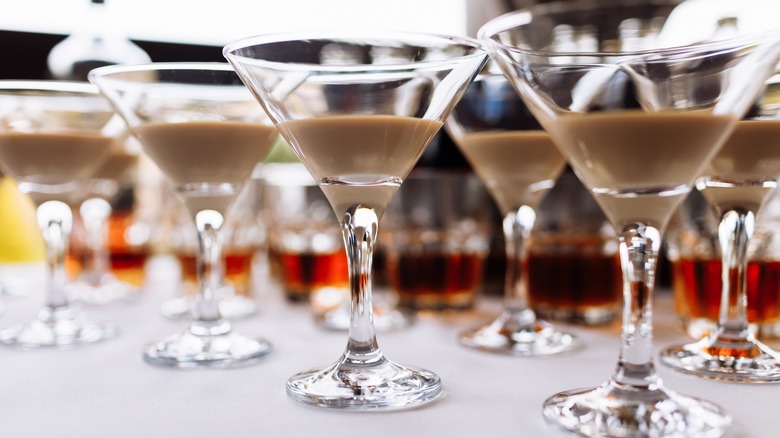 A row of martini glasses filled partway with Irish cream liqueur.