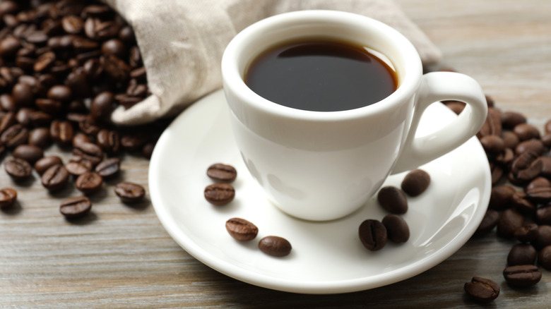 Cup of coffee surrounded by coffee beans