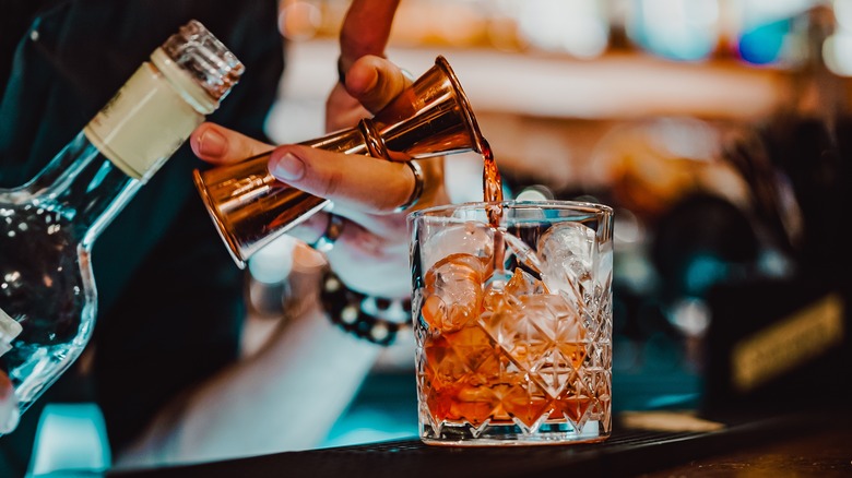 Pouring single Negroni cocktail over ice