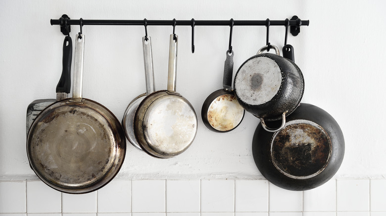 A rack of cooking pans dangle on a rack in a kitchen