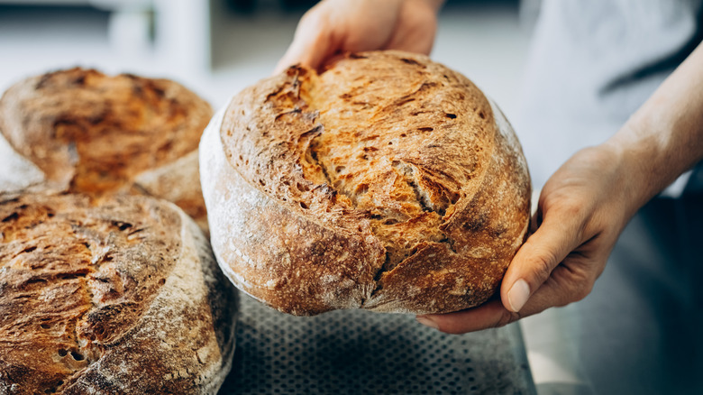 baker holding fresh loaf of sourdough bread