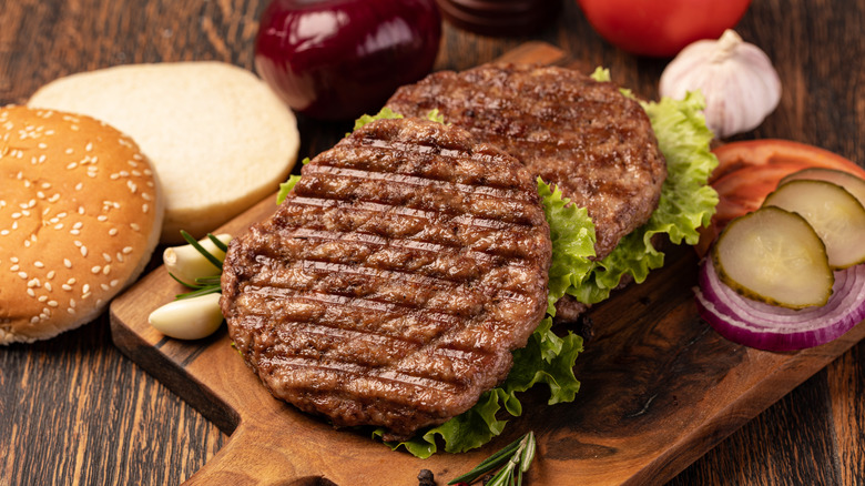 Cooked beef patties on board with burger ingredients