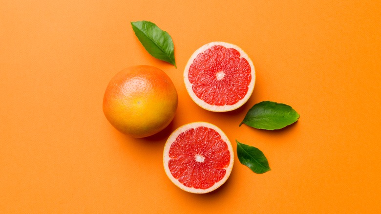 one whole grapefruit next to two halves of a cut grapefruit