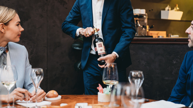 Sommelier presenting wine to table in a restaurant