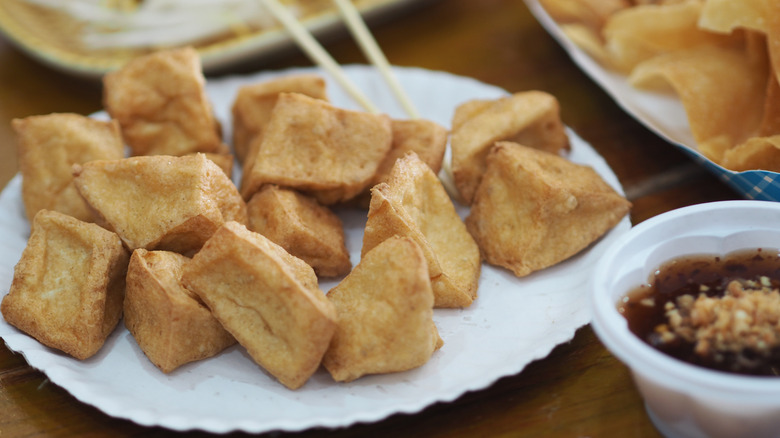 A plate of fried tofu with a peanut dipping sauce