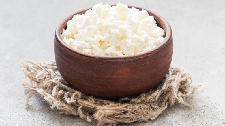 Cottage cheese in clay bowl on burlap towel