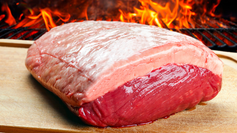 A raw picanho steak in front of a open fire