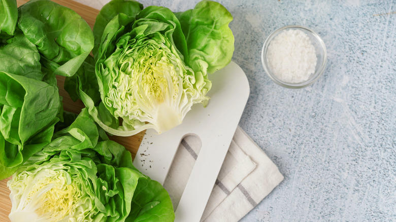 A head of Boston lettuce is sliced in half next to a bowl of flaky salt