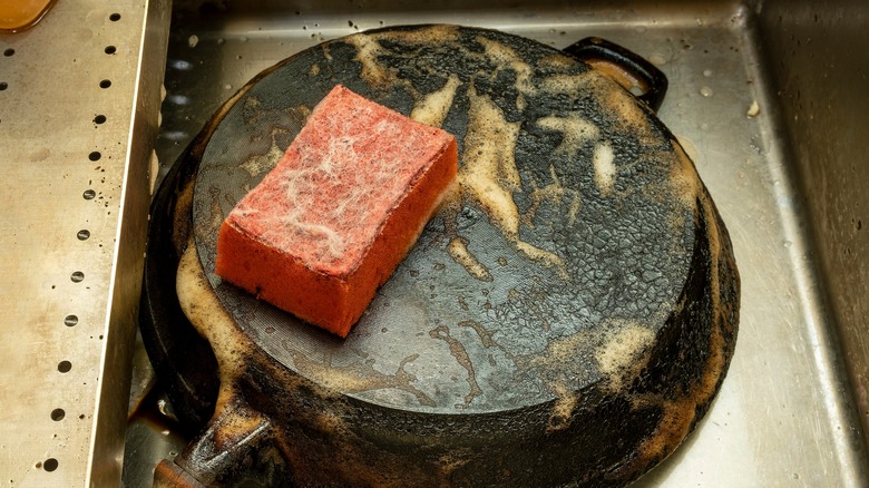 scrubbing rusty iron pan with sponge