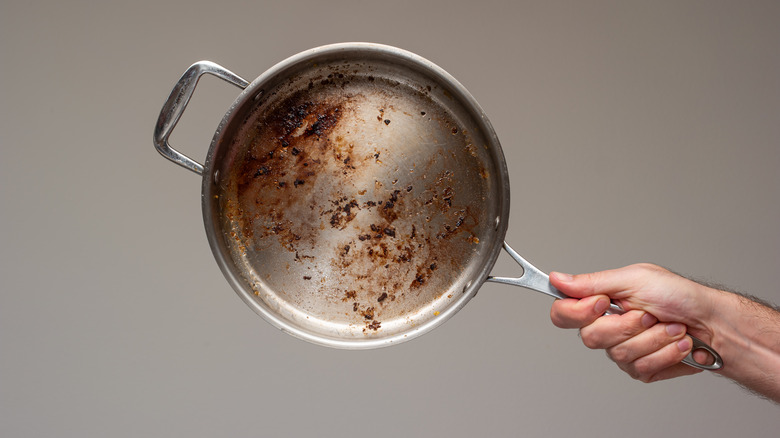 Person holding a dirty aluminum pan