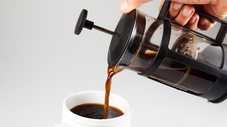 Person pouring French press coffee into cup