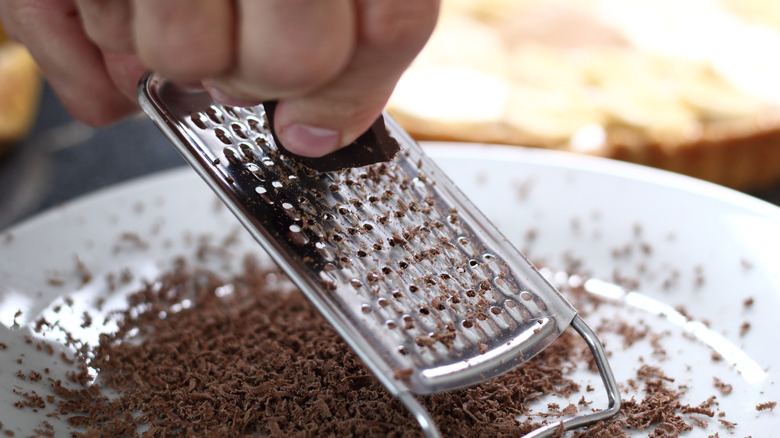 Person grating chocolate on Microplane