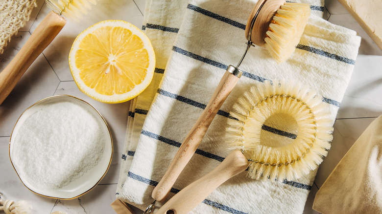 A sliced lemon next to cleaning brushes