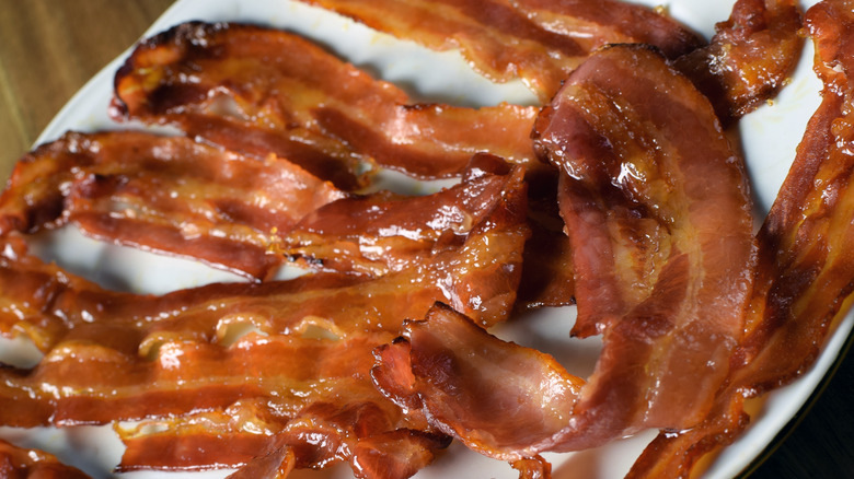 Strips of candied bacon with syrup on a white plate
