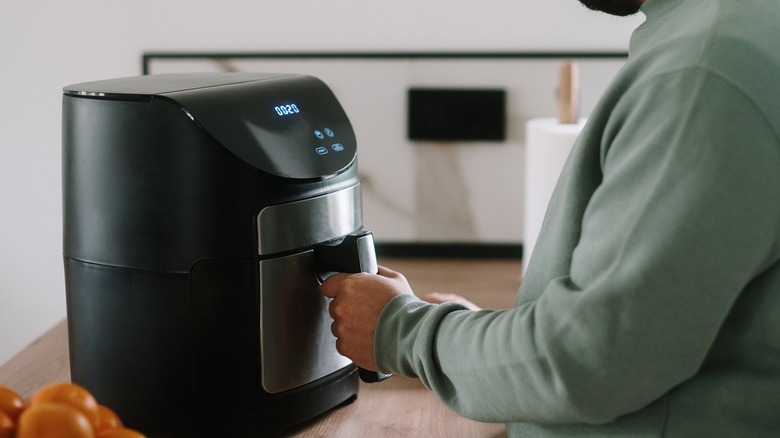 closeup of man using an air fryer