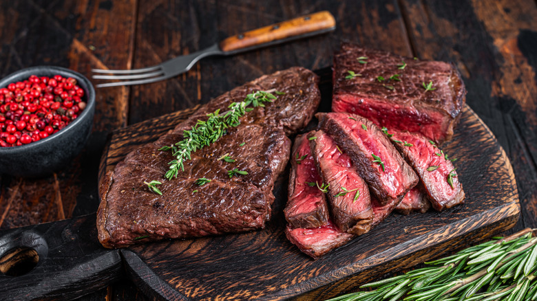 Grilled skirt steak on a cutting board with herbs