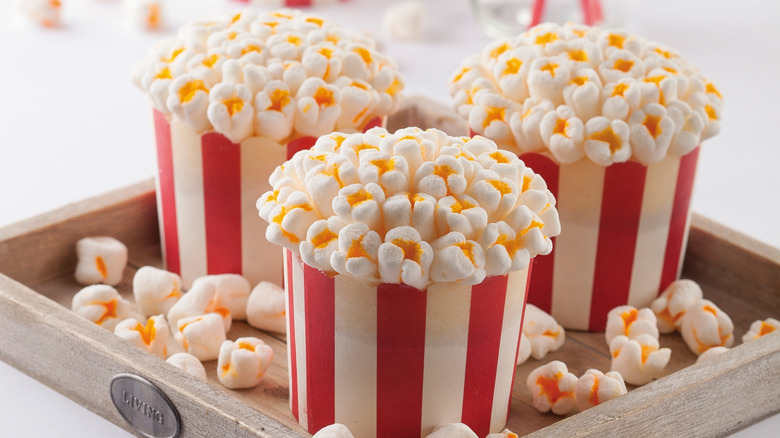 Cupcakes made in the shape of a popcorn bucket on a wooden plate with a white background