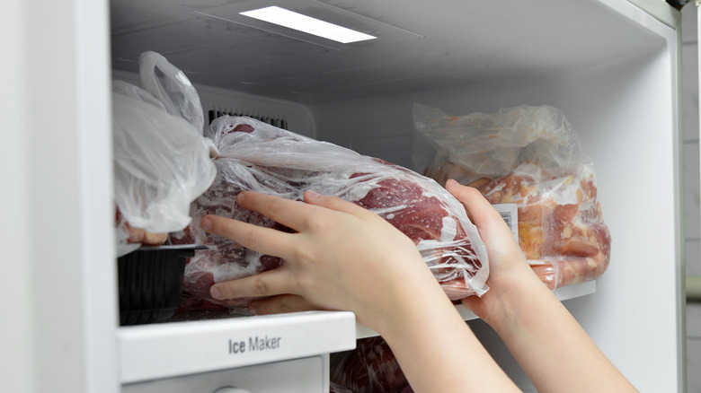 Hands taking meat from freezer