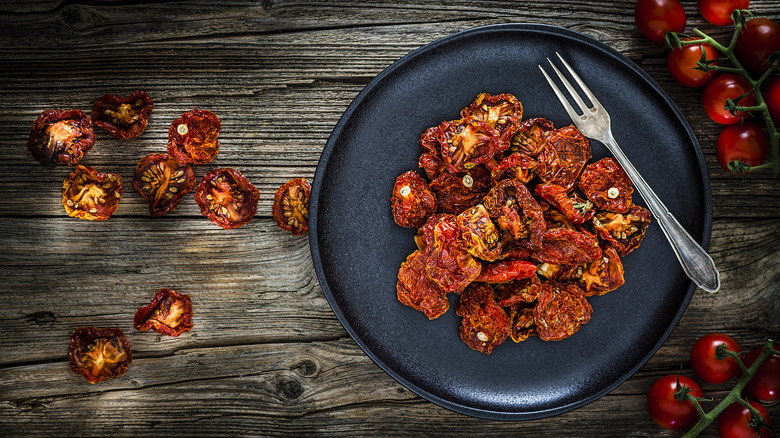 Dehydrated tomatoes on black plate next to fork