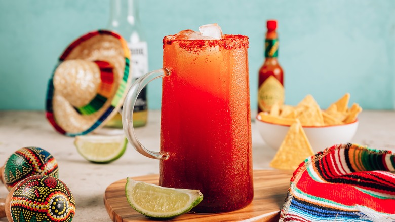 michelada with beer, sombrero, maracas, ponchom, hot sauce, tortilla chips, and lime 