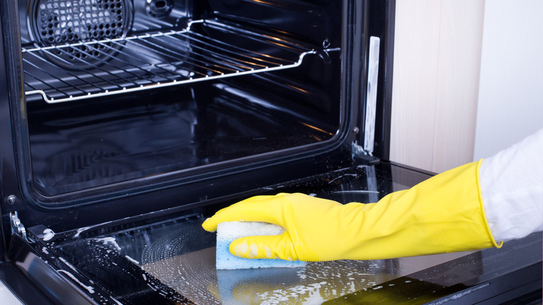 person with gloves cleaning inside the oven