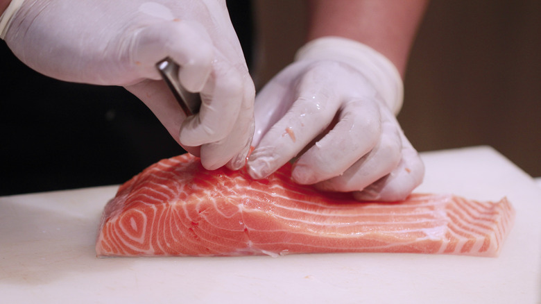 Man tweezing pin bones from salmon fillet