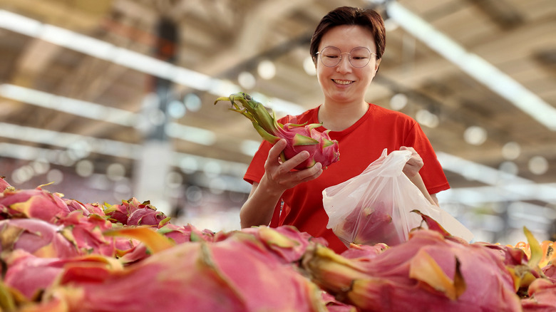 Woman bagging dragon fruit at supermarket