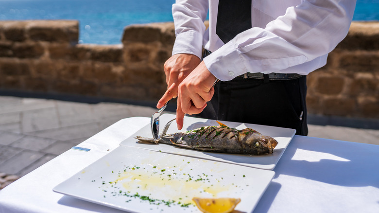 Waiter removing fish tail tableside
