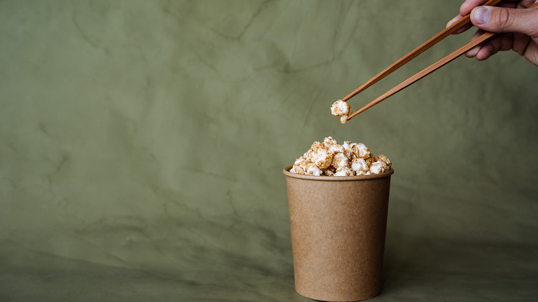 Person grabbing popcorn with chopsticks