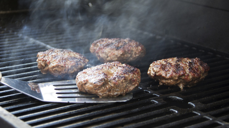 four burger patties on the grill