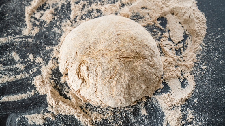 ball of dough and flour on black surface