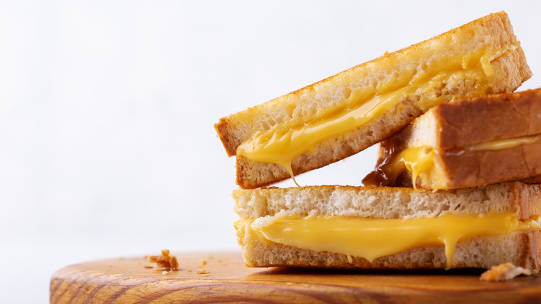 Stacked halves of grilled cheese on a wooden board.