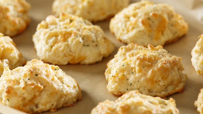 A slew of cheddar biscuits on a parchment paper lined baking tray