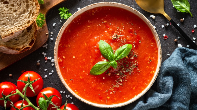 A bowl of tomato soup garnished with fresh basil.