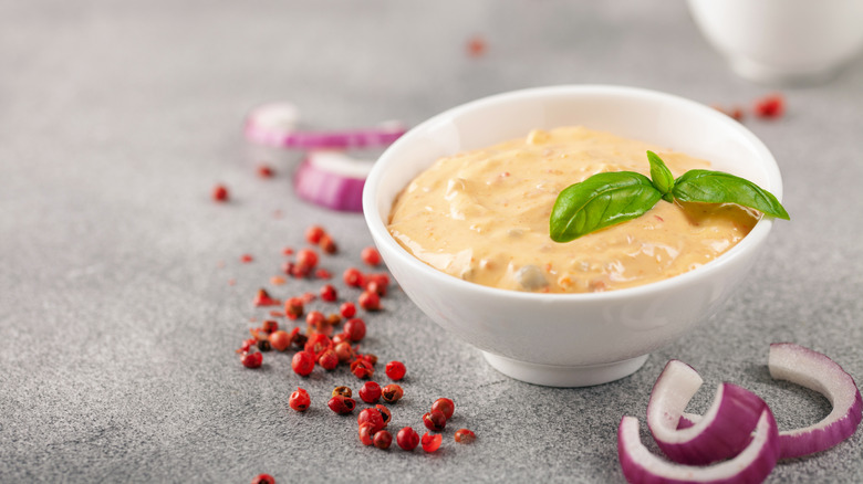 A yogurt salsa dressing sits in a white dish with a fresh herb garnish on top