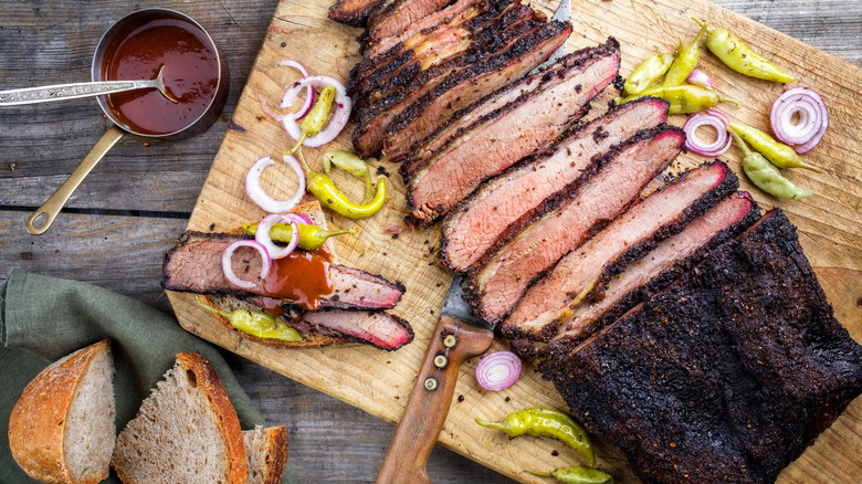 BBQ meat on board with sauce, peppers, and bread