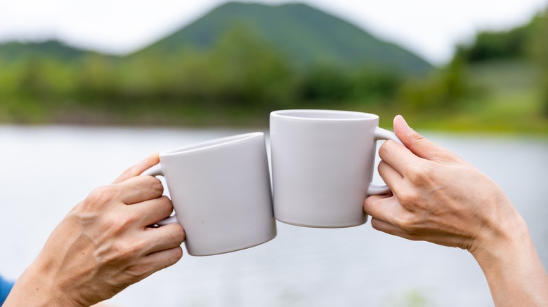 Cheers with coffee cups with a mountain in the background