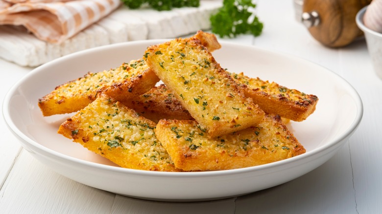 Slices of garlic bread in a white ceramic bowl