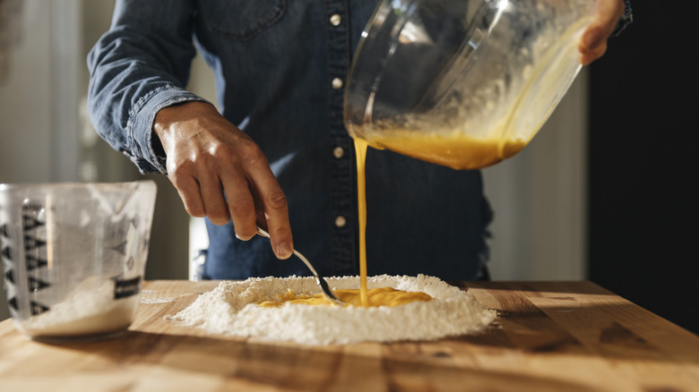 pouring egg into flour to make homemade pasta