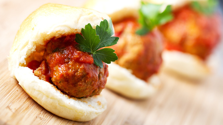 A meatball slider with tomato sauce and a green herb garnish