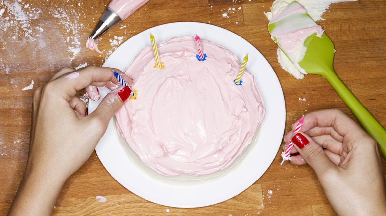 putting candles on pink cake