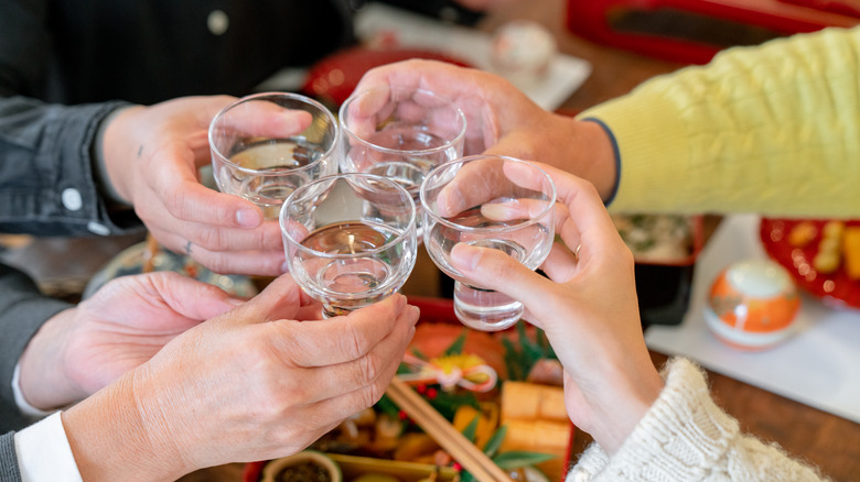 People toasting with sake over sushi spread