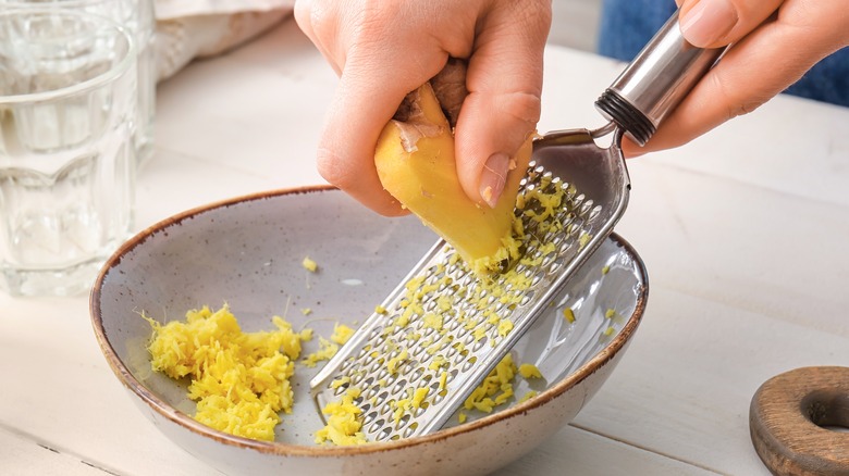 grating ginger root into a bowl