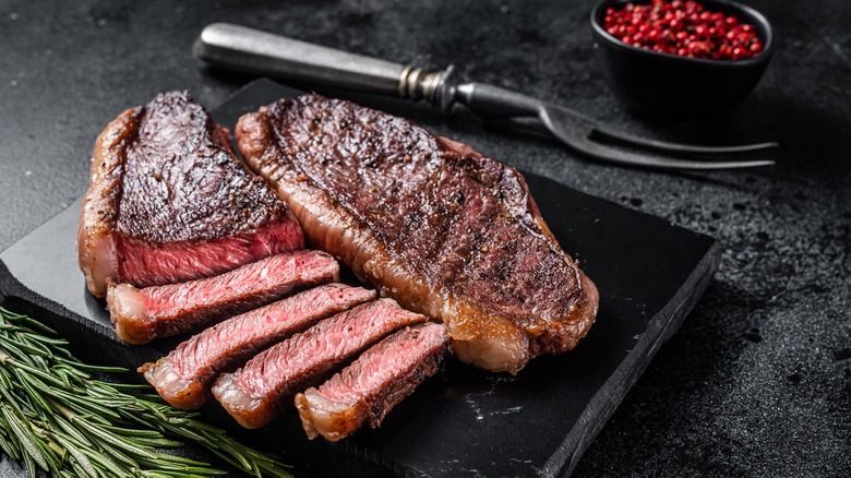 steaks on marble board - one partially sliced