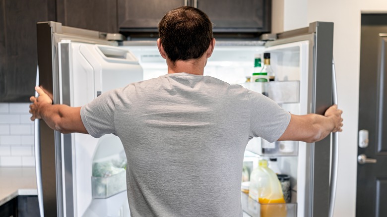 man looking into refrigerator
