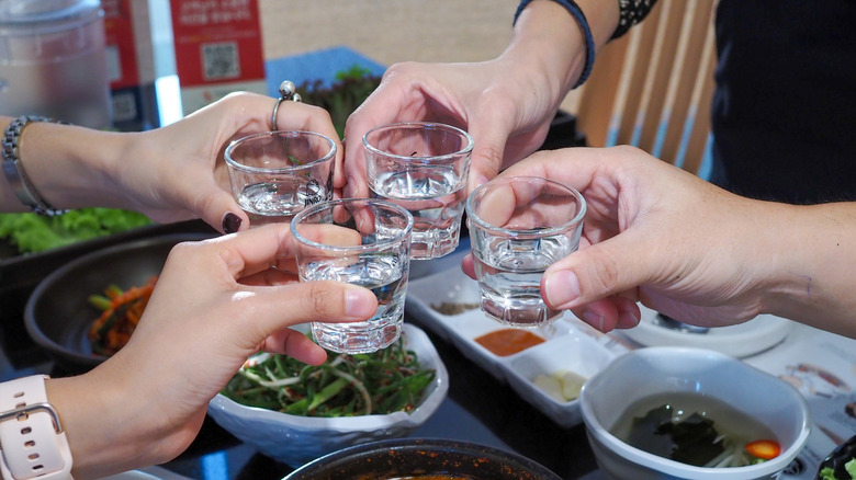 Four people toast with shots of soju